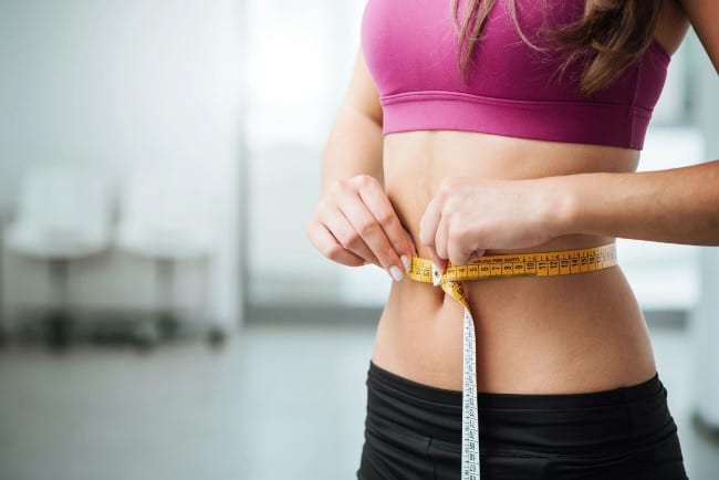 slim-figure-woman-measuring-belly-with-measuring-tape